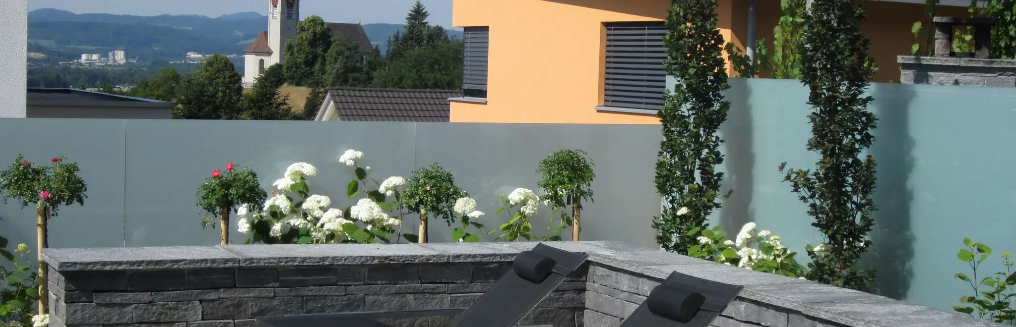 Eine Terrasse mit einer Bank und einer Wand, die mit bunten Blumen geschmückt ist.